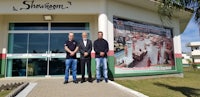 three men standing in front of a building with a large advertisement